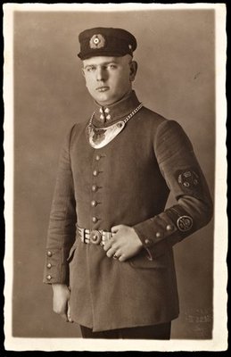 De man is gekleed in een uniformjas van de Fahnenträger des -Wehrwolfs- Ortsgruppe Hr. Königsberg i.Pr. -Bezirk Ost- en een pet.jpg